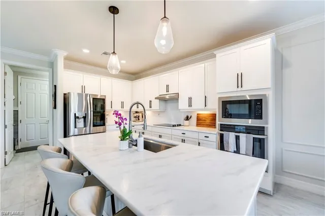 a large kitchen with stainless steel appliances granite countertop a stove a refrigerator a oven a sink a dining table and chairs with wooden floor