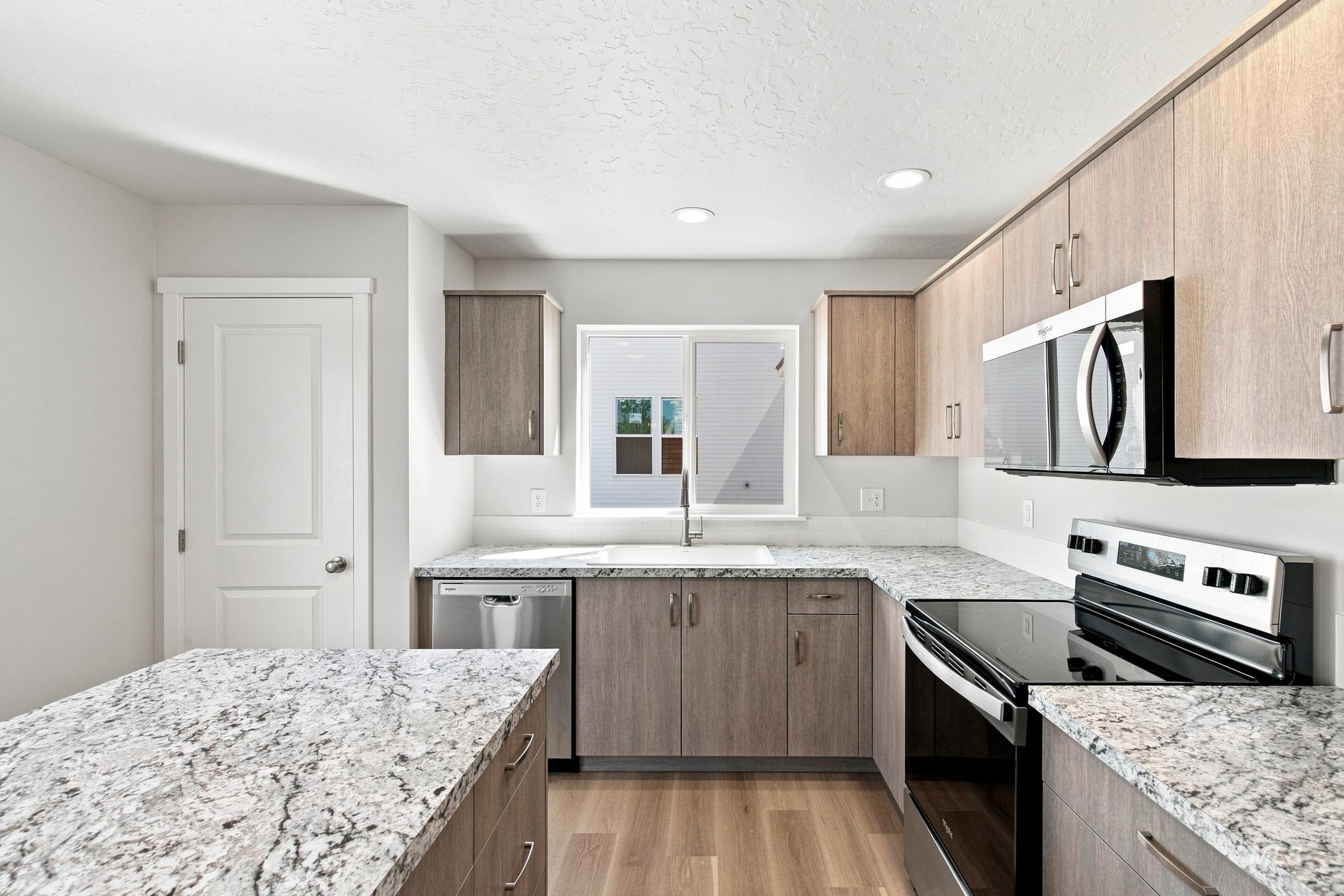 464 Merlin Court Middleton, ID 83644 - Photo 4 of 26 Kitchen featuring light wood-finish cabinetry, speckled countertops, stainless steel appliances, and wood-finish flooring