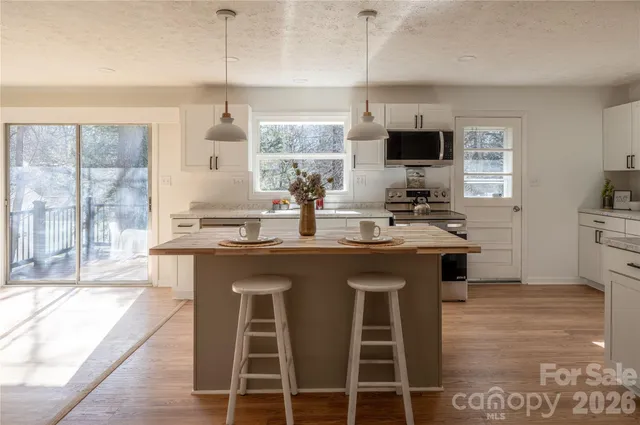 a kitchen with stainless steel appliances granite countertop a stove top oven a sink dishwasher a dining table and chairs with wooden floor