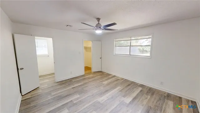 an empty room with wooden floor and windows