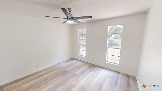 an empty room with windows and fan