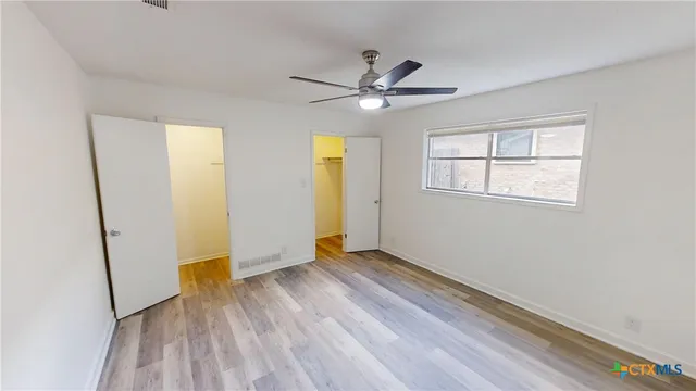 a view of empty room with wooden floor and fan