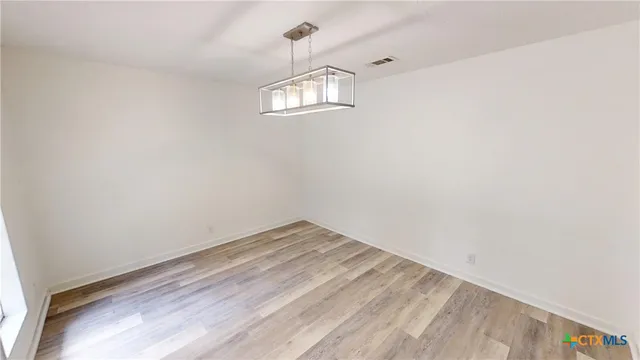 a view of empty room with wooden floor and ceiling fan