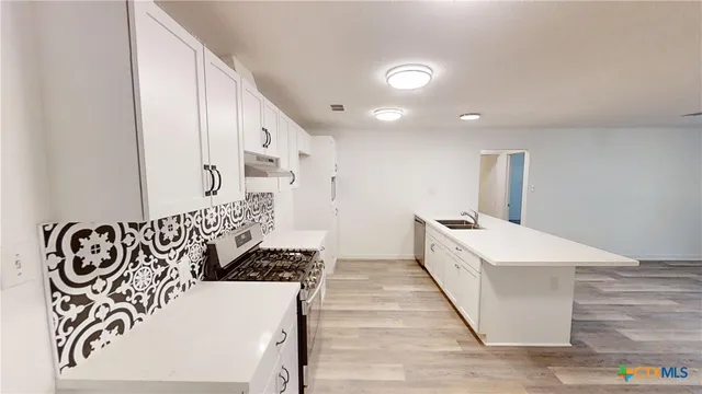 a large white kitchen with a large window and stainless steel appliances