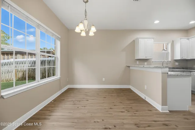 a kitchen with stainless steel appliances granite countertop a stove top oven a sink a refrigerator white cabinets and wooden floor