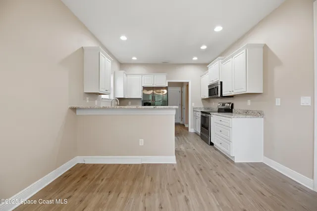 a kitchen with granite countertop white cabinets and stainless steel appliances