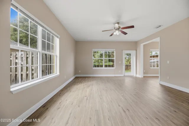 a view of an empty room with a window and wooden floor