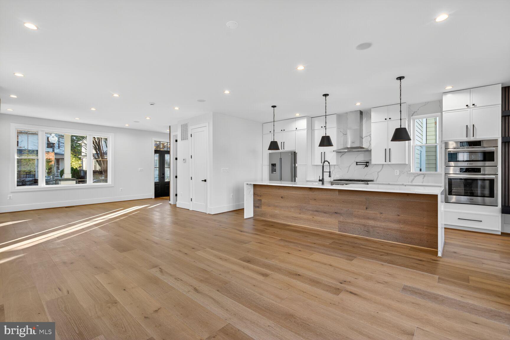 1209 Decatur Street Northwest Washington, DC 20011 - Photo 11 of 54 a large kitchen with kitchen island a stove a refrigerator a sink and white cabinets with wooden floor
