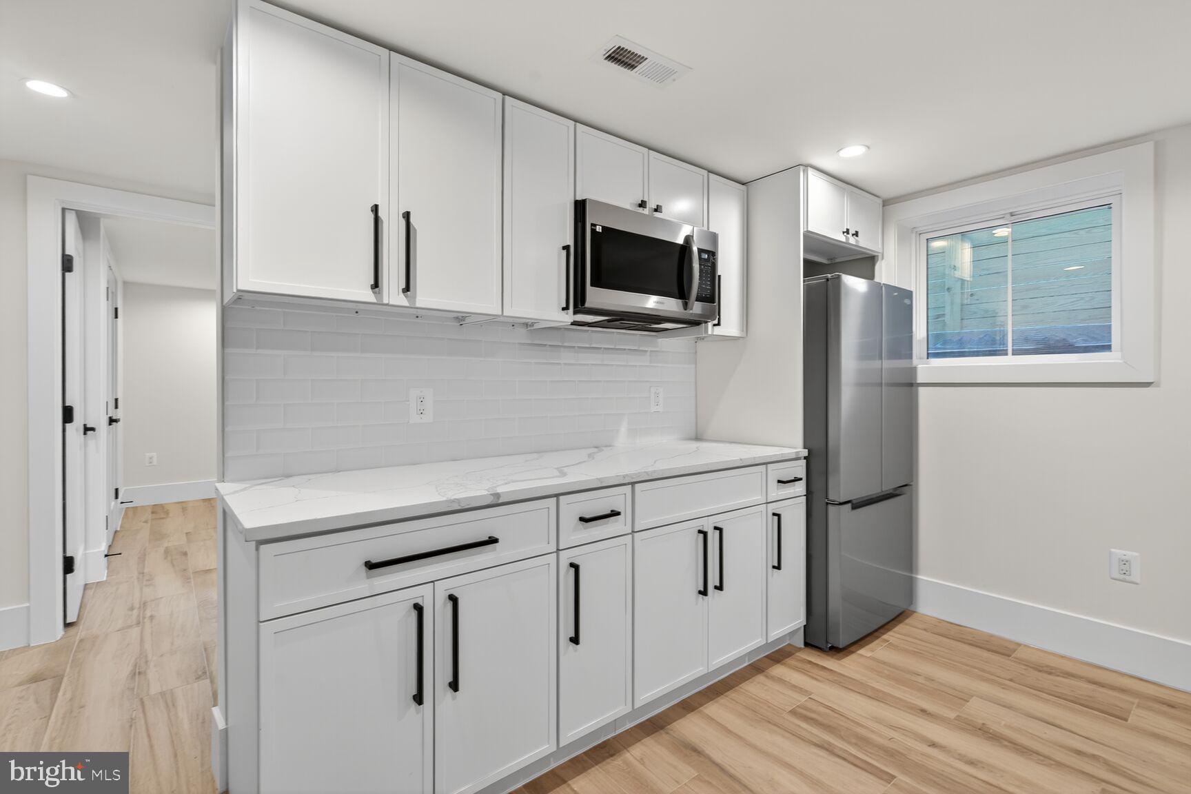 1209 Decatur Street Northwest Washington, DC 20011 - Photo 42 of 54 a kitchen with stainless steel appliances white cabinets and wooden floors