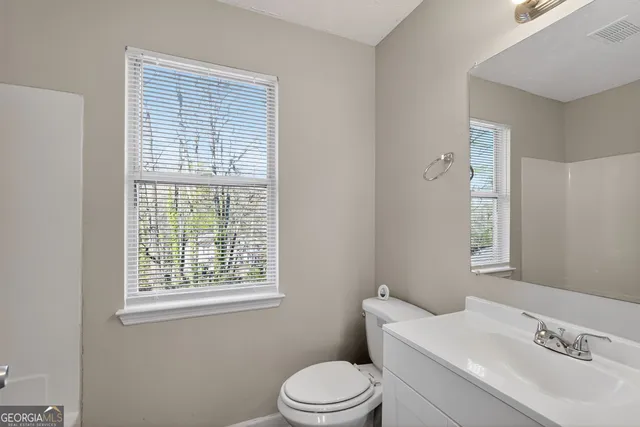 a bathroom with a sink vanity granite toilet and a window