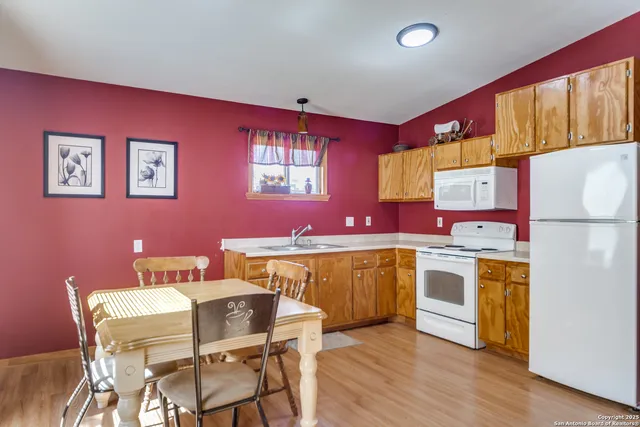 a kitchen with stainless steel appliances granite countertop a dining table chairs cabinets and wooden floor