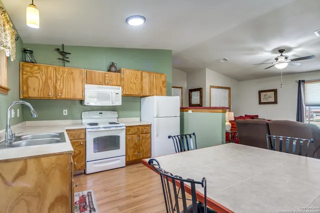 a kitchen with stainless steel appliances granite countertop a refrigerator a sink dishwasher a stove and white countertops with wooden floor