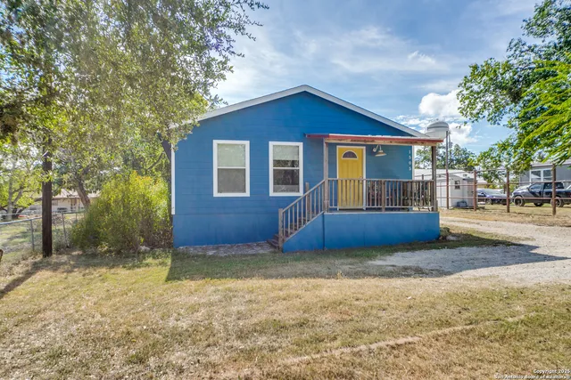 a view of a house with a yard and large tree