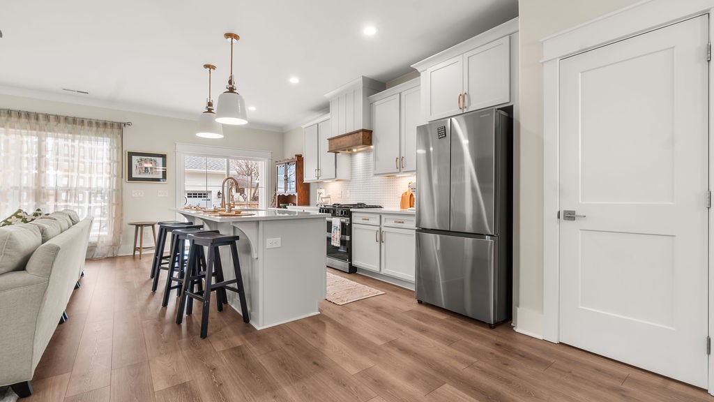 819 North Maple Street Murfreesboro, TN 37130 - Photo 5 of 64 a kitchen with kitchen island a refrigerator a stove a dining table and chairs with wooden floor