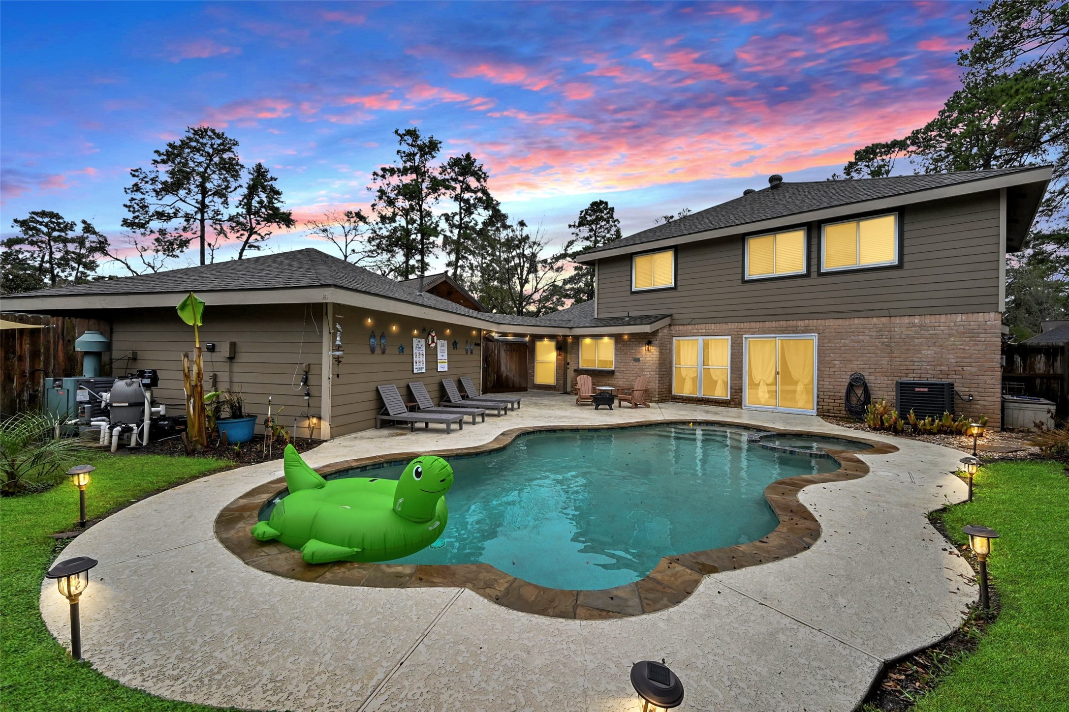 a view of a house with a swimming pool lawn chairs and a fire pit