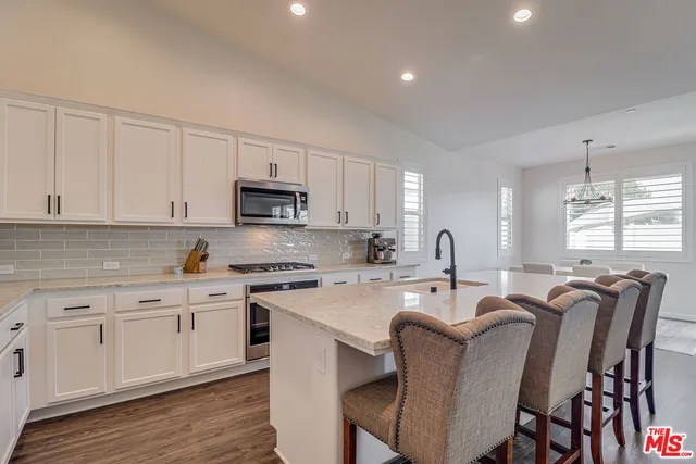 a open dining room with stainless steel appliances granite countertop a sink a stove a dining table and chairs