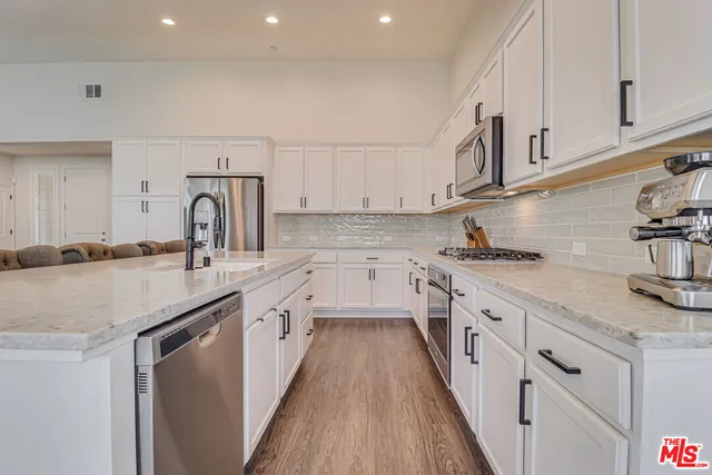 a kitchen with granite countertop kitchen island a sink appliances cabinets and a counter top space