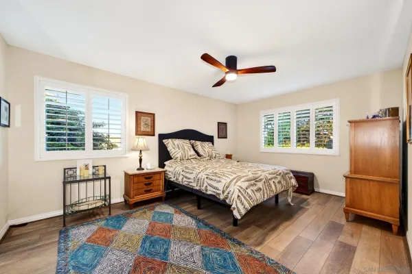 a bedroom with a bed a ceiling fan and a large window