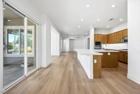 a view of kitchen with kitchen island wooden floor window and stainless steel appliances