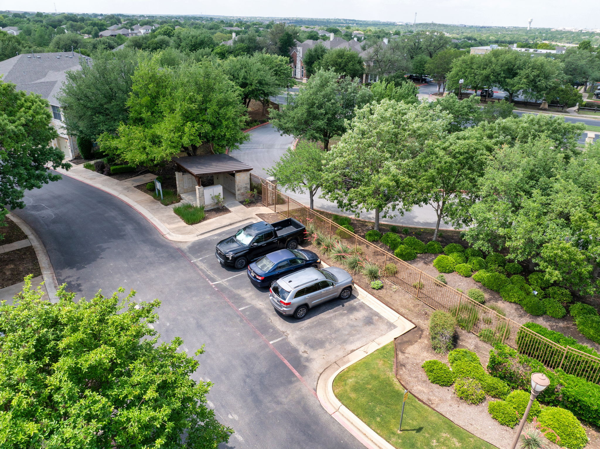 14815 Avery Ranch Boulevard, Unit 1401 Austin, TX 78717 - Photo 31 of 38 Paved parking area featuring designated spaces, surrounded by lush trees and manicured shrubbery