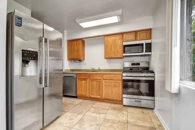 a kitchen with stainless steel appliances granite countertop a refrigerator and a sink
