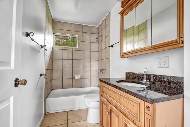 a bathroom with a granite countertop sink a toilet and shower