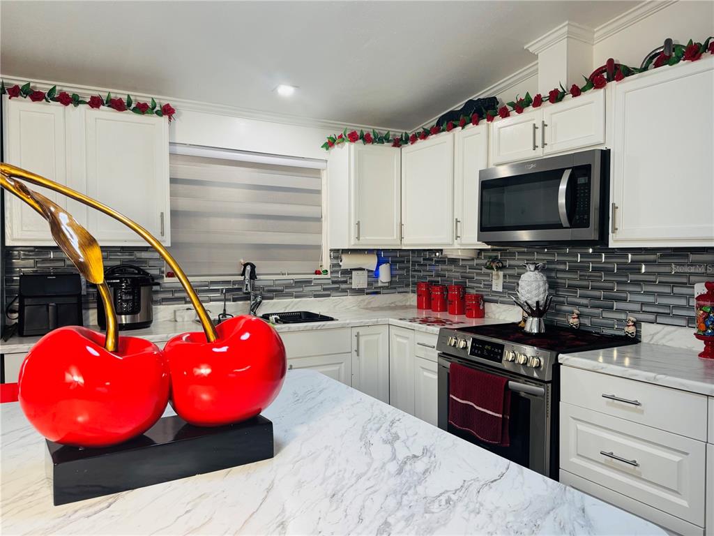 18304 Cedarhurst Road Orlando, FL 32820 - Photo 3 of 24 a kitchen with a sink a stove and cabinets