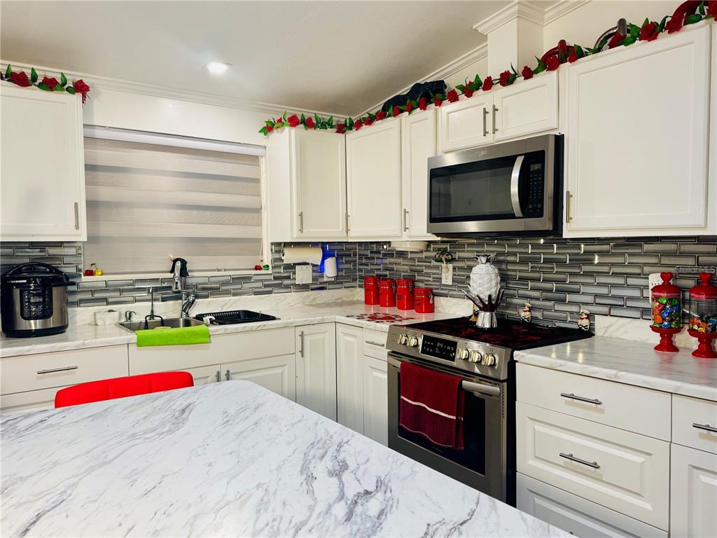 18304 Cedarhurst Road Orlando, FL 32820 - Photo 4 of 24 a kitchen with kitchen island granite countertop a sink stainless steel appliances and cabinets
