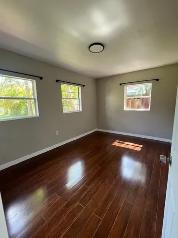 a view of empty room with wooden floor and fan