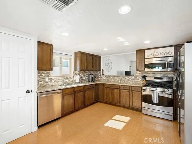 a kitchen with stainless steel appliances granite countertop a stove top oven a sink dishwasher and a refrigerator