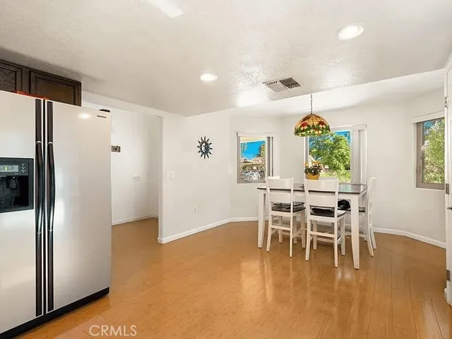 a kitchen with stainless steel appliances kitchen island granite countertop a refrigerator a stove and a dining table with wooden floor