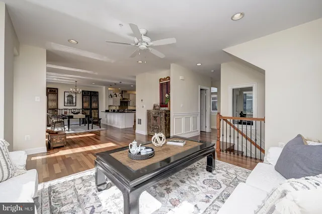 a large kitchen with granite countertop a stove a sink and white cabinets with wooden floor