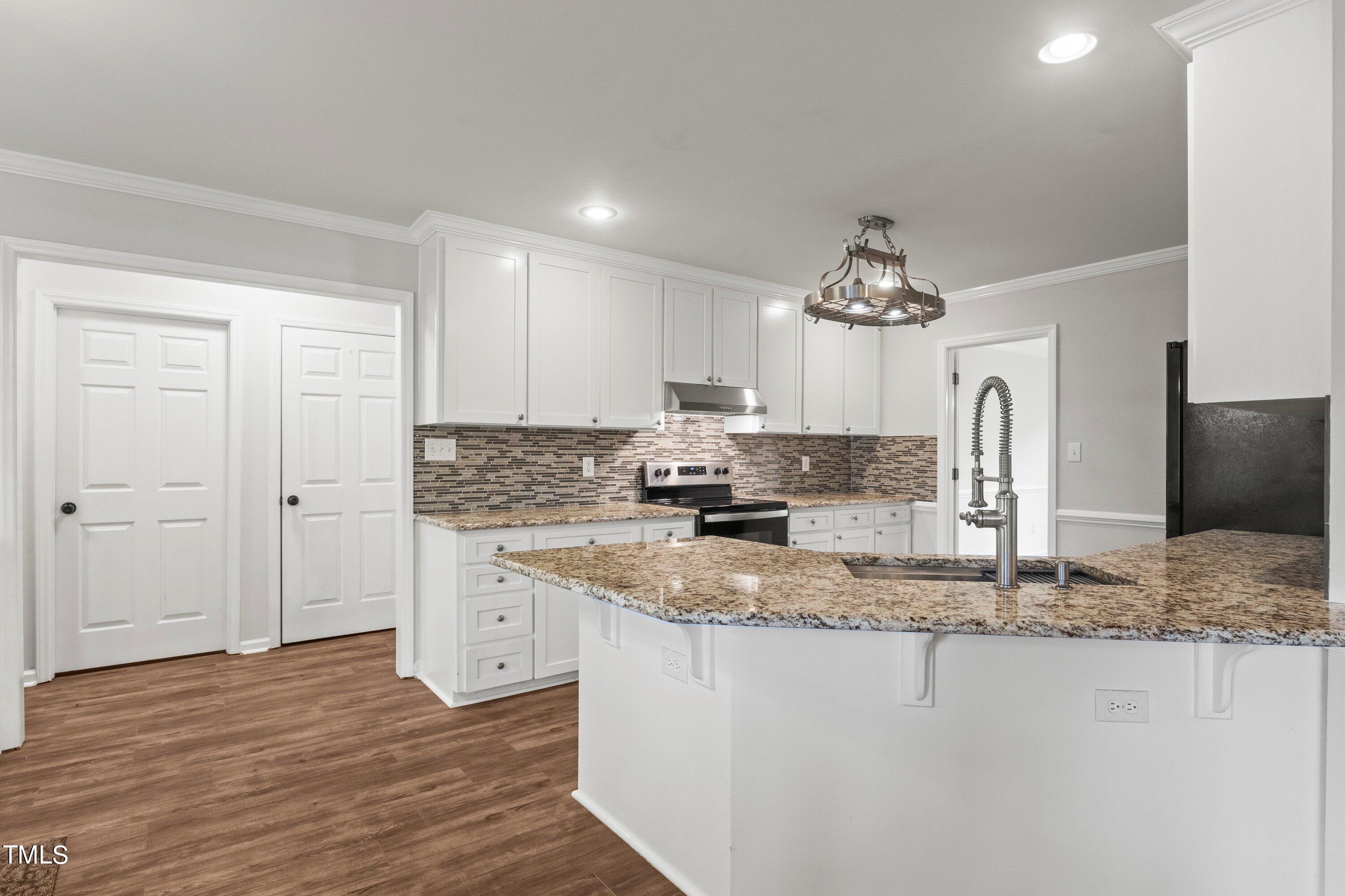 505 Castleberry Road Clayton, NC 27527 - Photo 14 of 38 a kitchen with kitchen island granite countertop a sink cabinets and wooden floor