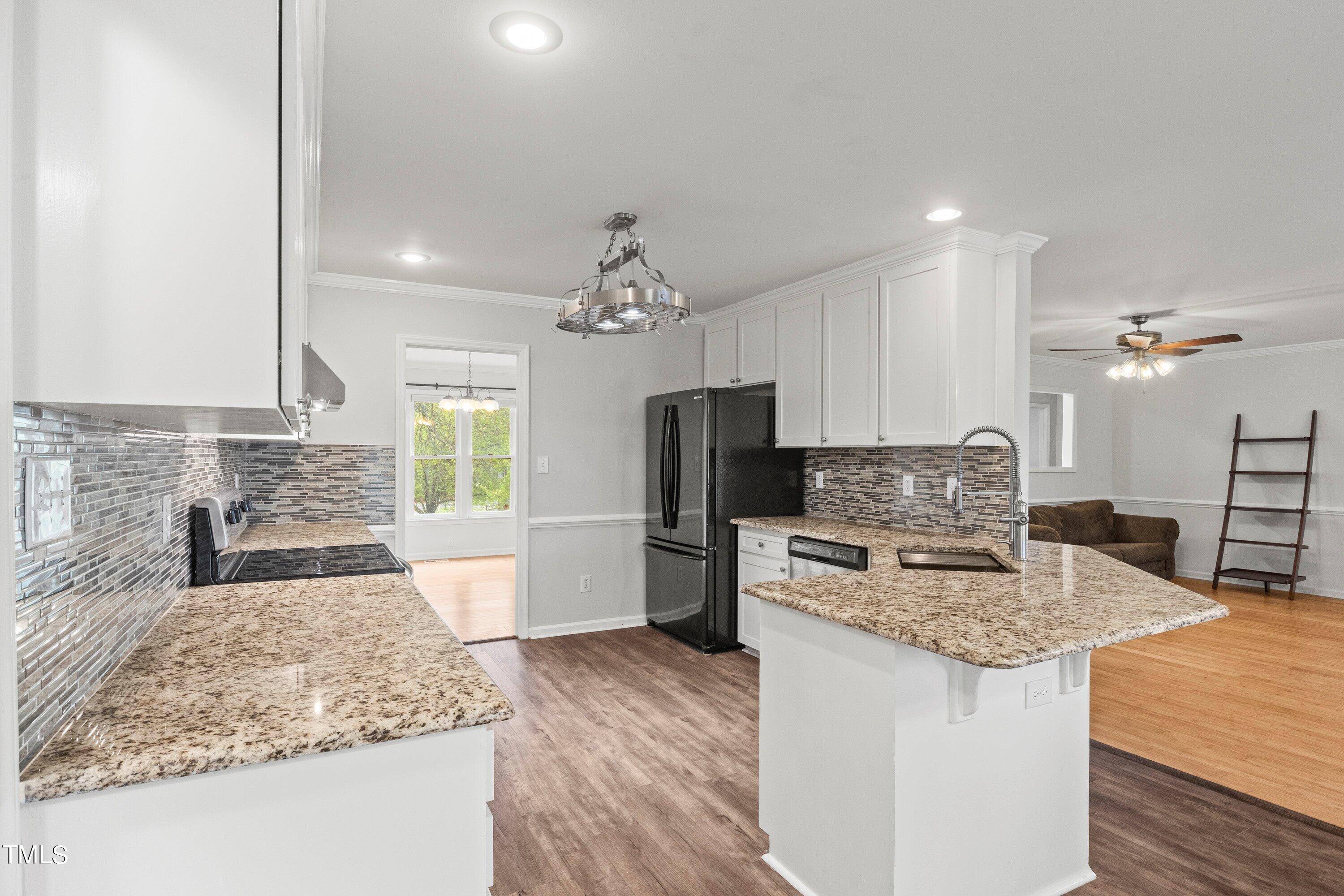 505 Castleberry Road Clayton, NC 27527 - Photo 15 of 38 a kitchen with kitchen island granite countertop stainless steel appliances a sink stove refrigerator and cabinets
