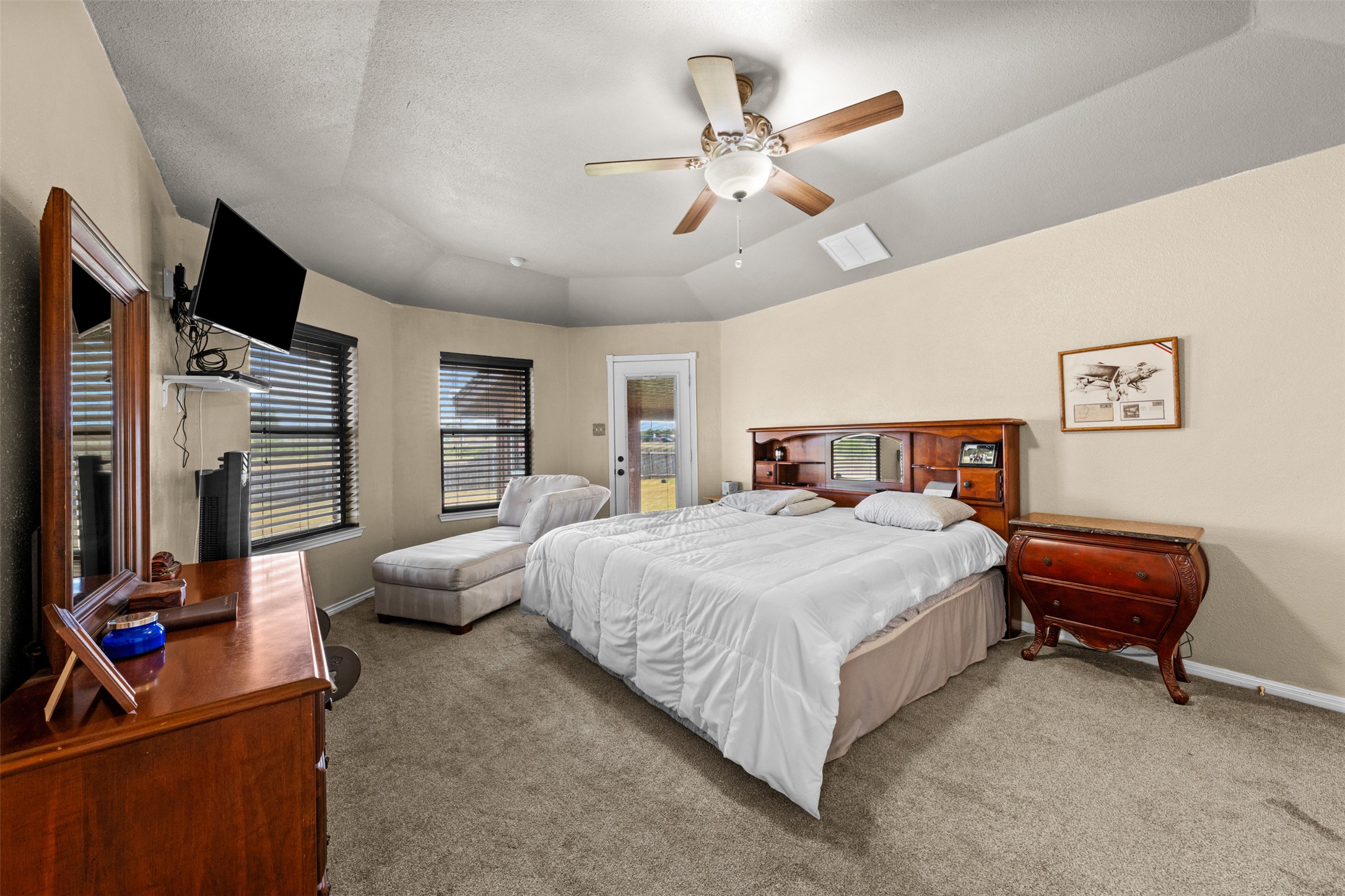 1512 Panther Loop Pflugerville, TX 78660 - Photo 15 of 40 A generously proportioned bedroom with carpeted floors features a ceiling fan and a door leading to outdoor space.