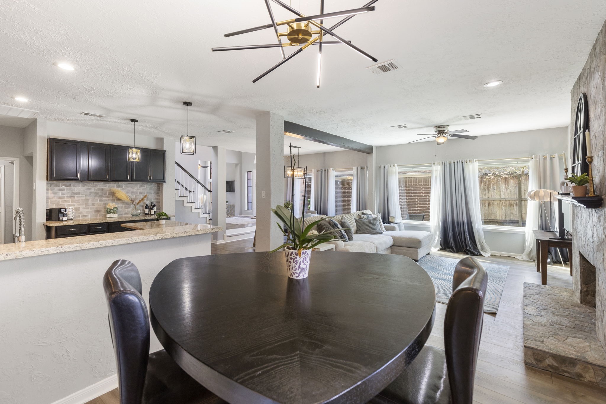 2110 Paso Rello Drive Houston, TX 77077 - Photo 18 of 41 This open-concept living area features a modern dining space, cozy living room with a stone fireplace, and a sleek kitchen with granite countertops and pendant lighting. Large windows provide ample natural light and offers a welcoming atmosphere.