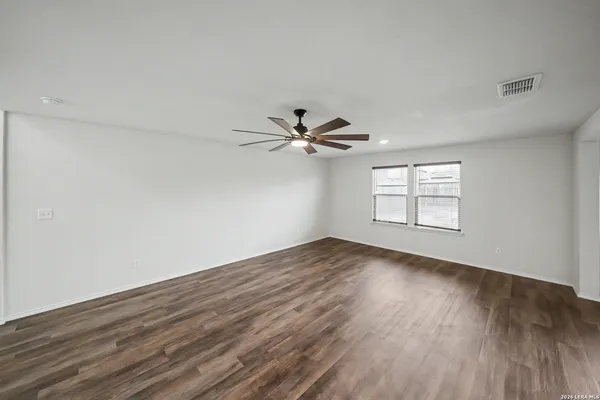an empty room with wooden floor fan and windows