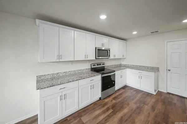 a kitchen with granite countertop white cabinets and white appliances