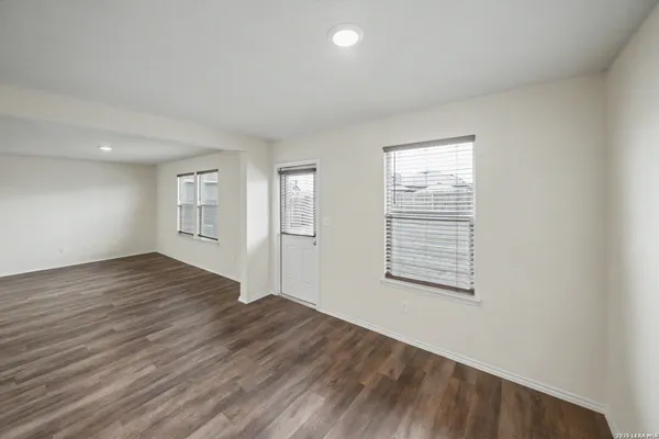 an empty room with wooden floor and windows