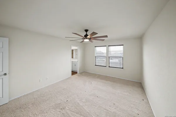 an empty room with windows and ceiling fan