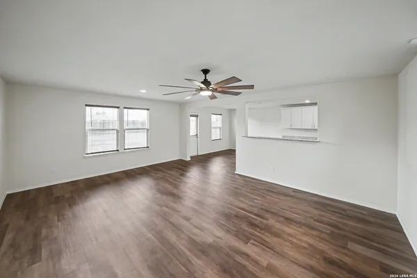 an empty room with wooden floor chandelier and windows