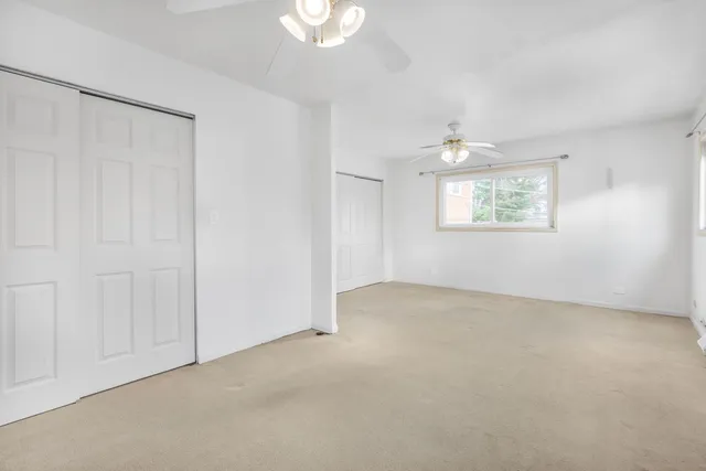 an empty room with windows and chandelier fan