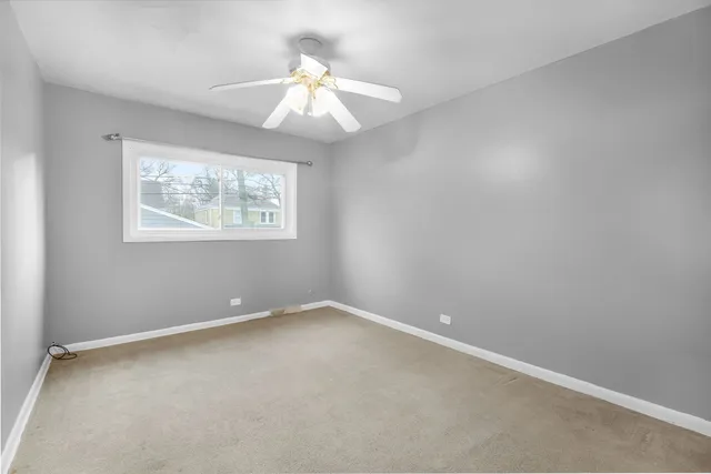 an empty room with windows and chandelier fan