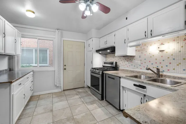 a kitchen with granite countertop a sink a stove and cabinets