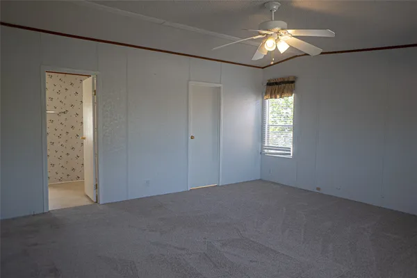 an empty room that has a chandelier fan and a window