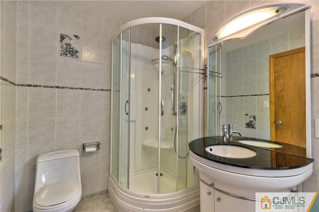 221 North Hill Road Colonia, NJ 07067 - Photo 19 of 25 a bathroom with a granite countertop sink toilet a mirror and shower