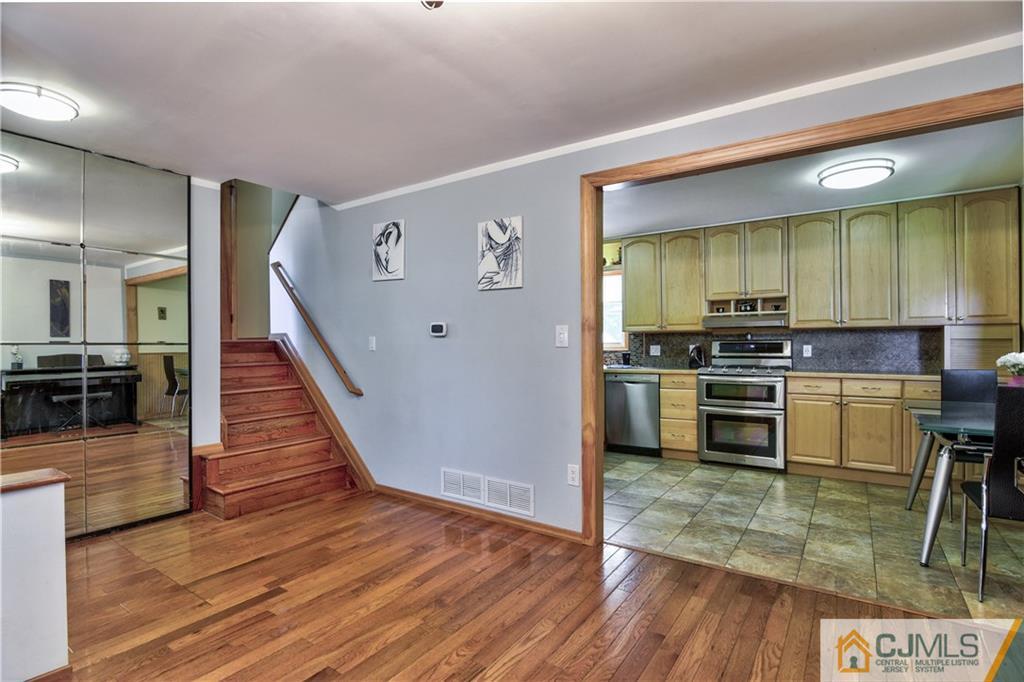 221 North Hill Road Colonia, NJ 07067 - Photo 7 of 25 a kitchen with wooden floor white cabinets and stainless steel appliances