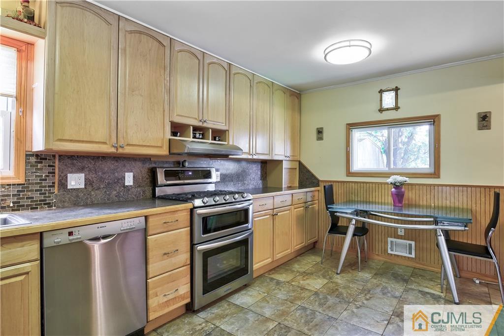 221 North Hill Road Colonia, NJ 07067 - Photo 9 of 25 a kitchen with stainless steel appliances kitchen island granite countertop a sink a stove a dining table and chairs