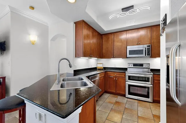 a kitchen with granite countertop a stove sink and refrigerator