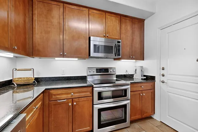 a kitchen with granite countertop wooden cabinets and stainless steel appliances